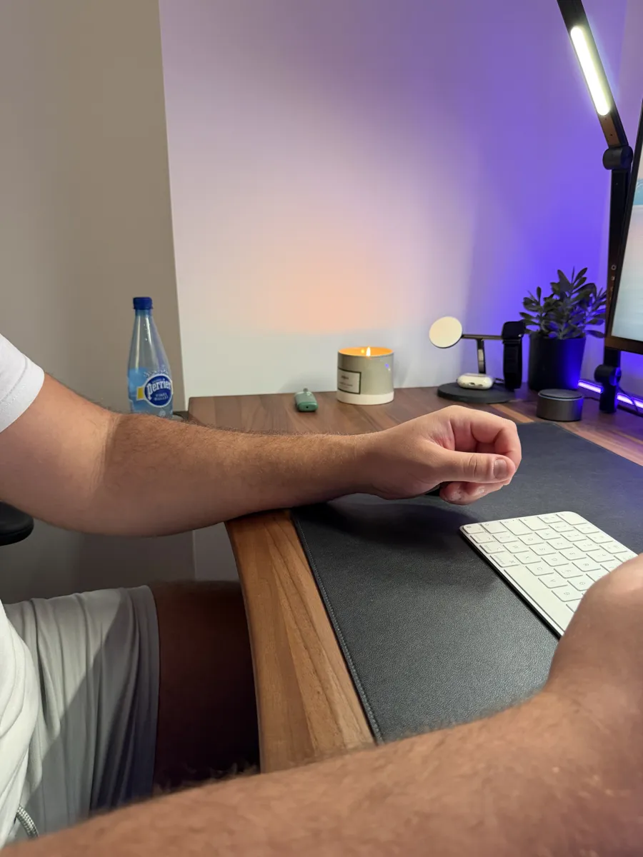 Avant-bras posé dans la découpe ergonomique du plateau Ergohide en noyer